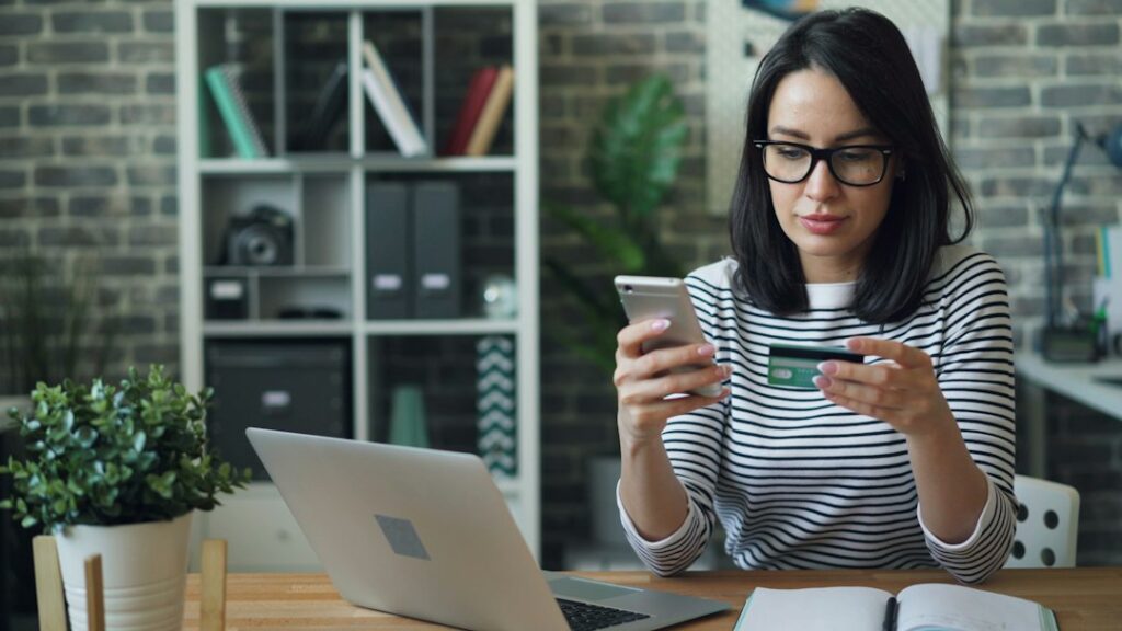 Pessoa utilizando celular e cartão em uma operação de pagamento